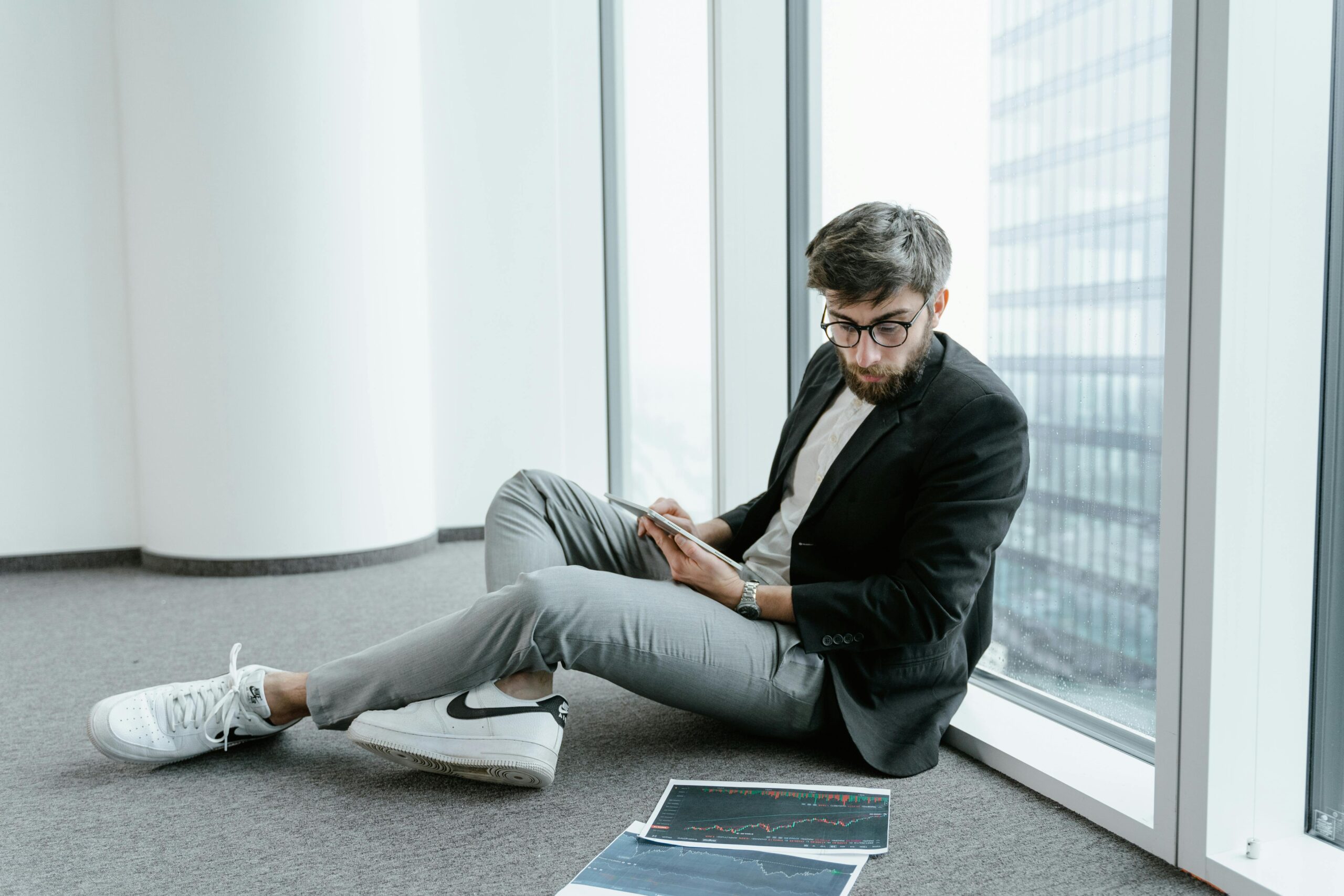 A man in an office setting using a tablet to analyze stock market data with graphs.